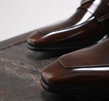 Close-up of brown high-shine leather and sharp square toe construction on formal bit loafers