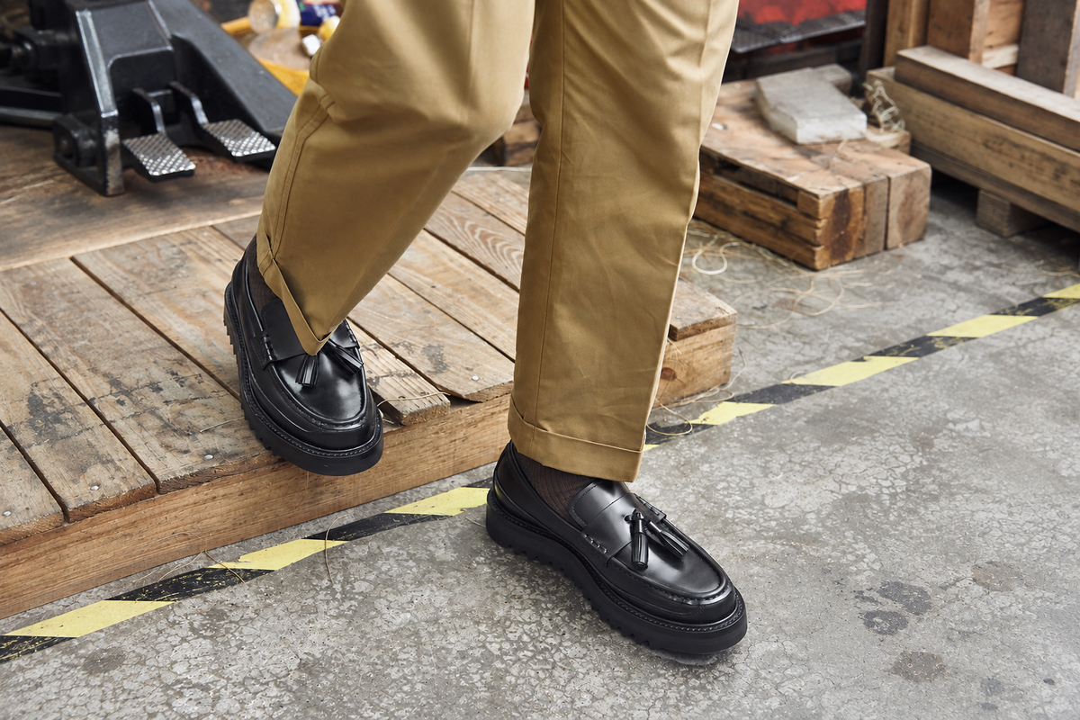 Black Hector Maden tassel loafers worn with cuffed khaki trousers